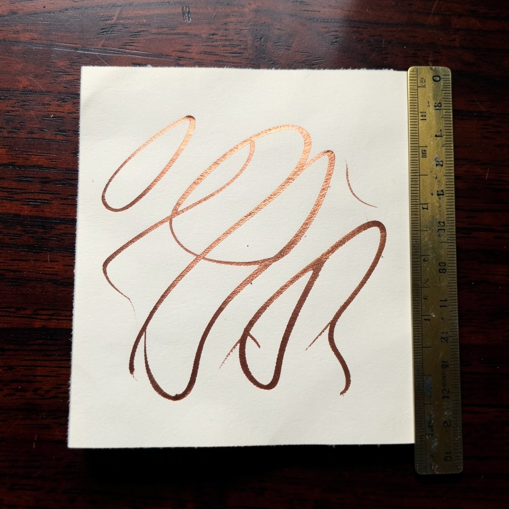 Close view of ivory paper with abstract copper curves on dark wood